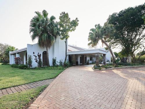 a white house with palm trees and a driveway at The Sunbird Guesthouse in Gingindlovu