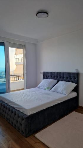 a large bed in a bedroom with a large window at Pirro Luxury Apartment in Sarandë