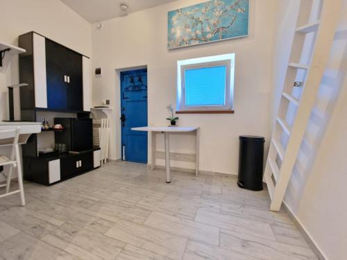 a kitchen with a table and a blue door at Apartament Vincent in Ustronie Morskie