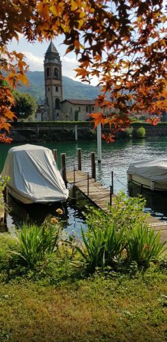 a boat is docked at a dock with a church at Hotel Fonte dei Fiori in Caslano