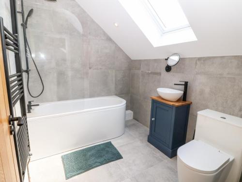 a bathroom with a tub and a toilet and a sink at Stabal in Gwalchmai