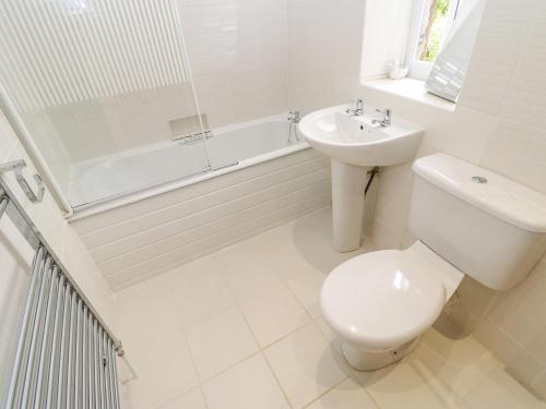 a white bathroom with a toilet and a sink at Church View Cottage in Bishop Auckland