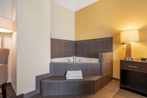 a bathroom with a tub and a sink at Sleep Inn & Suites Miles City in Miles City