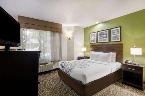 a hotel room with a bed and a flat screen tv at Sleep Inn Hanes Mall in Winston-Salem