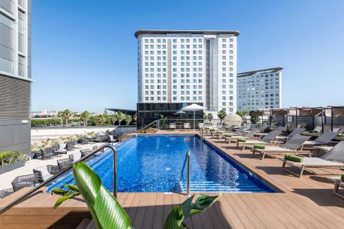 a hotel pool with lounge chairs and a tall building at Melia Valencia in Valencia