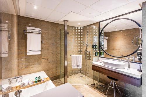 une salle de bain avec un lavabo, une baignoire et un miroir dans l'établissement Melia Valencia, à Valence