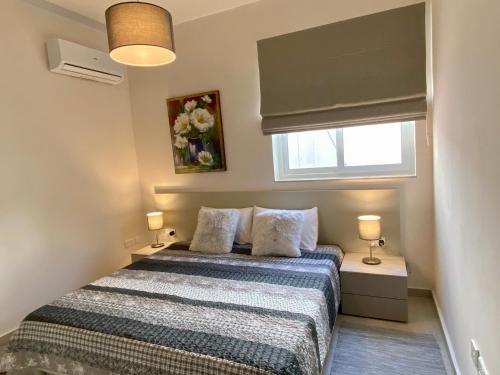 a bedroom with a bed with two lamps and a window at Maltese Garden Villa in Mosta