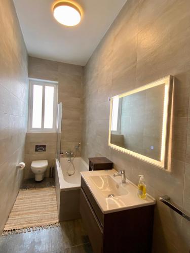 a bathroom with a sink and a toilet and a mirror at Maltese Garden Villa in Mosta