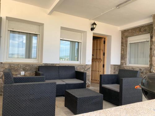 uma sala de estar com sofás, cadeiras e janelas em Villa de Gredos em Navarredonda de Gredos