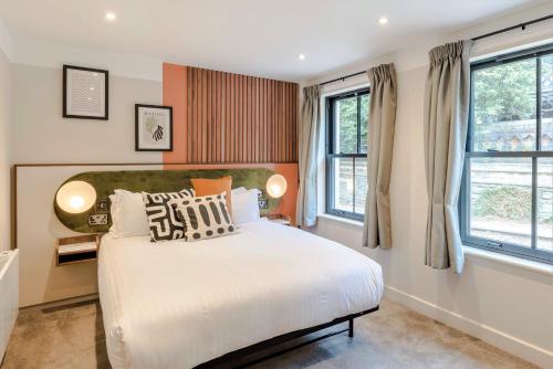 a bedroom with a large bed and two windows at Your Apartment I Arabica House in Bristol