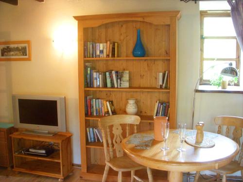 um quarto com uma mesa e uma televisão e uma estante de livros em The Nest - Thatched seaside country cottage for two em Stokeinteignhead