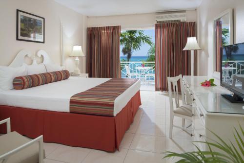 a bedroom with a large bed and a balcony at SeaGarden Beach Resort - All Inclusive in Montego Bay