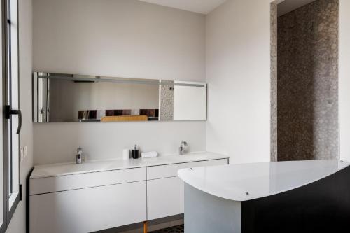 a white bathroom with a sink and a mirror at Edgar Suites - Bordeaux Meriadeck in Bordeaux