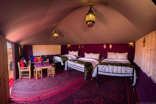 a room with four beds and a table and chairs at Ali & Sara's Desert Palace in Merzouga