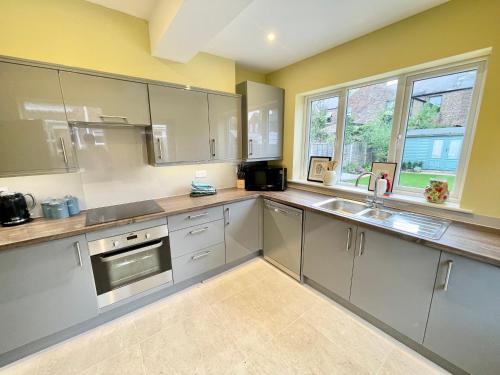 a kitchen with gray cabinets and a sink and windows at Central Townhouse with free off road parking and garden in York