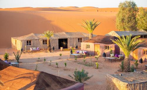 an old house in a desert with palm trees at Ali & Sara's Desert Palace in Merzouga