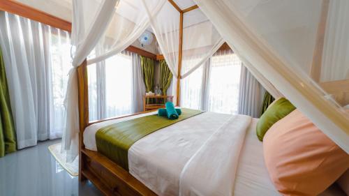 a bedroom with a canopy bed and a window at Odiyana Bali Retreat in Banyuwedang