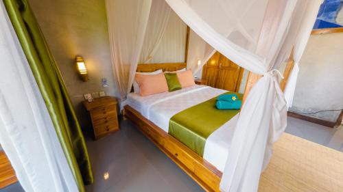 a bedroom with a bed with a canopy at Odiyana Bali Retreat in Banyuwedang