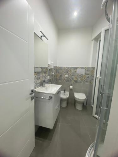 a white bathroom with a toilet and a sink at Porta Saracena Rooms in Agropoli