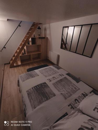 - une chambre mansardée avec 2 lits et un escalier dans l'établissement Le Petit Nogentais, à Nogent-le-Roi