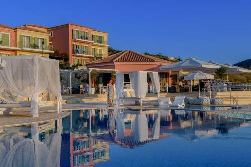 a pool with white chairs and tables and buildings at Petani Bay Hotel - Adults Only in Vovikes