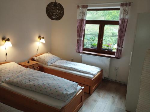 two beds in a room with a window at Hostinec pod úbočou in Valaská