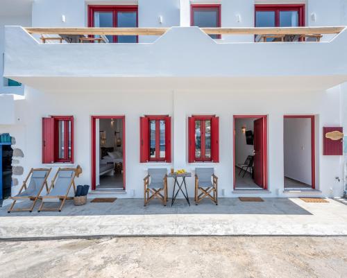 a white house with red windows and chairs at Magic Klima I in Klima