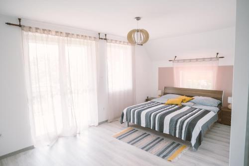 a bedroom with a bed with a striped blanket at MacskaFészek Vendégház in Kissomlyó