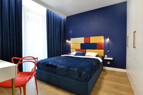 a blue bedroom with a bed and a red chair at Plac Unii - Barcelona 64 in Gdynia