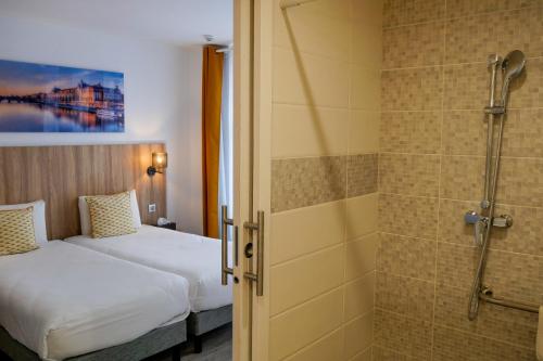 a hotel room with a bed and a shower at Kyriad Paris 10 - Canal Saint Martin - République in Paris