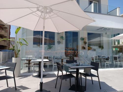 um pátio com mesas e cadeiras e um guarda-sol em Hotel Brienz em Bellaria-Igea Marina