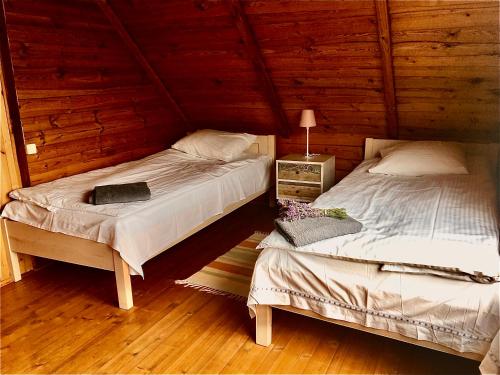 two beds in a room with wooden walls at Poilsio namelis Plateliuose in Plateliai