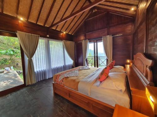 a bedroom with a large bed in a room with windows at Munduk V View House in Munduk