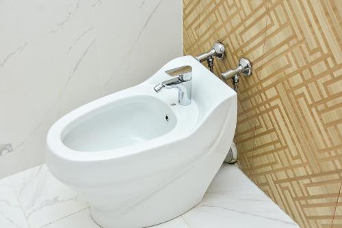 a white toilet in a bathroom with a sink at Ramada by Wyndham Turkistan in Türkistan