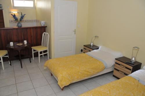 ein Hotelzimmer mit 2 Betten, einem Tisch und einem Stuhl in der Unterkunft Studio au manoir in Saint-Jouan-des-Guérets