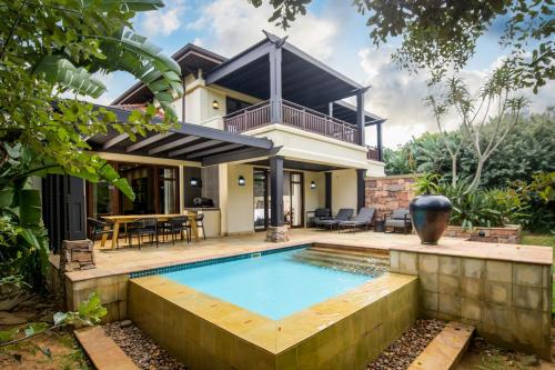 a house with a swimming pool in front of a house at The Capital Zimbali in Ballito