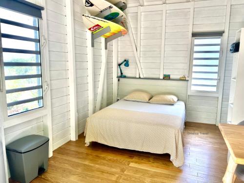 a small bedroom with a bed and a window at Le Surf Lodge, chambre avec vue mer dans un écrin de verdure in Deshaies