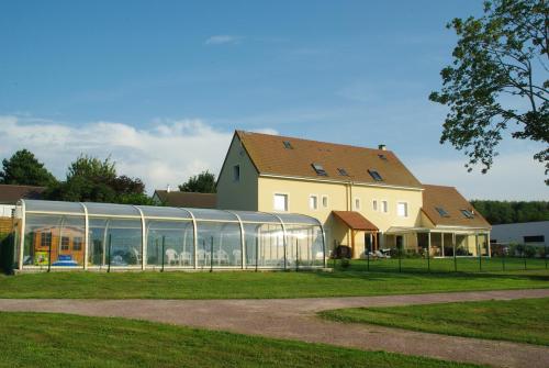 a building with a glass greenhouse next to a house at La Grimodière Chambre en rez de chaussée in Ranville