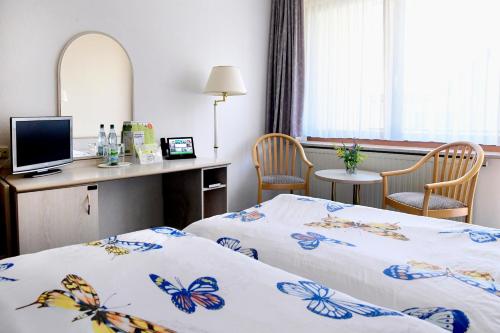 a hotel room with two beds and a desk at Hotel Im Kräutergarten in Cursdorf