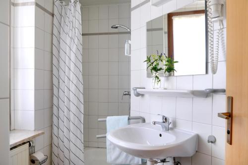 a white bathroom with a sink and a window at Hotel Im Kräutergarten in Cursdorf