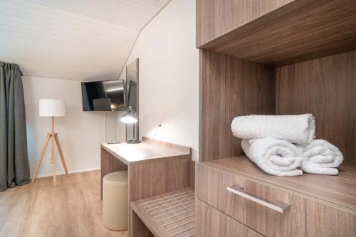 una habitación de hotel con toallas en un estante y TV en Relais Lucomagno en Olivone