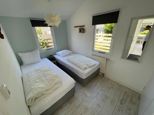a small room with two beds and two windows at Rekerlanden 253 in Schoorldam