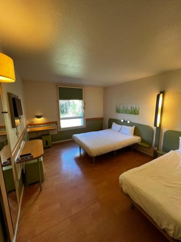 a hotel room with two beds and a window at Ibis Budget Marseille Est Porte d'Aubagne in Marseille