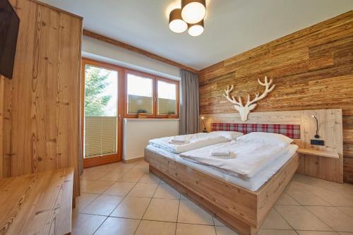 ein Schlafzimmer mit einem großen Bett an einer Holzwand in der Unterkunft Appartements Hollandia in Saalbach-Hinterglemm