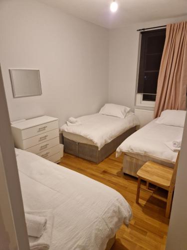 a room with two beds and a chair and a window at A Beautiful place in London