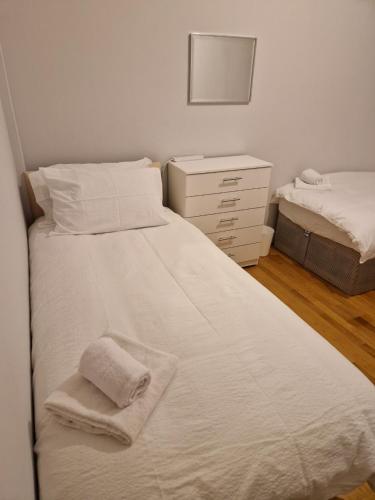 a bedroom with two beds and a dresser with towels at A Beautiful place in London