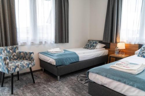 a hotel room with two beds and a chair at Malinowy Potok in Białka Tatrzanska