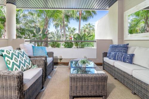 una sala de estar con muebles de mimbre y palmeras.  en FA- Luxury 2 bedroom apt Font Aloha, en Marbella