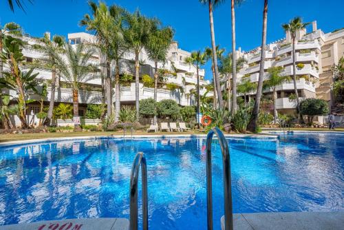 una gran piscina con palmeras frente a un edificio en FA- Luxury 2 bedroom apt Fuente Aloha, en Marbella