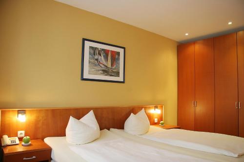 Habitación de hotel con cama con almohadas blancas en Hotel Verdi en Rostock